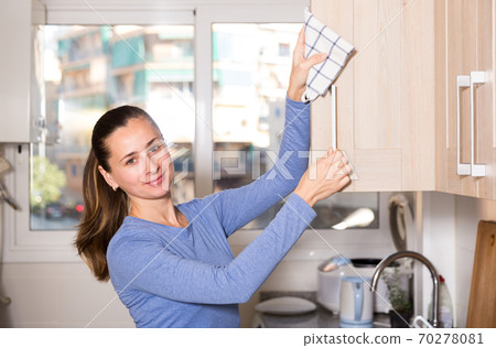 Smiling woman is cleaning surface on the kitchen at the home 70278081