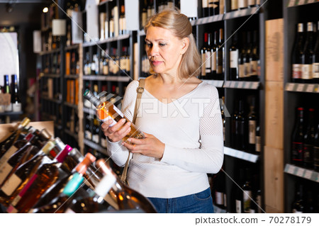Pretty woman choosing bottled wine 70278179