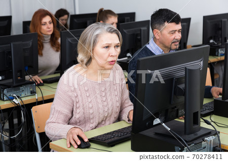 Young and older businesswomen and businessmen in open plan office Young and older businesswomen and businessmen in open plan office 70278411