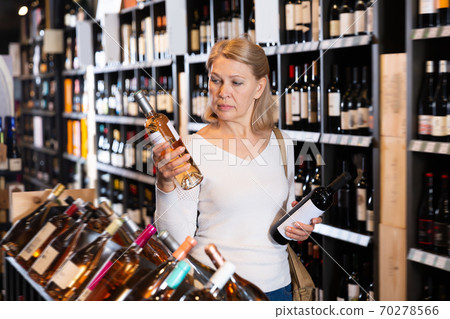 Glad woman choosing bottled wine 70278566