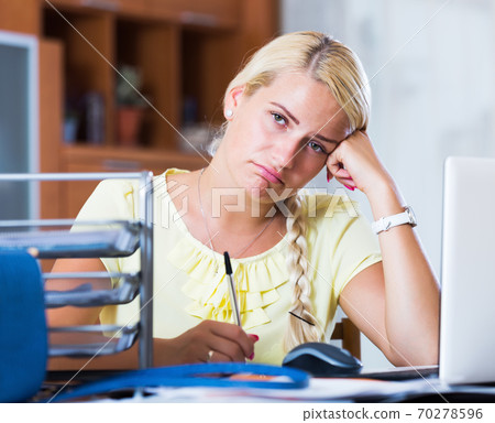 Tired woman sitting at desk 70278596