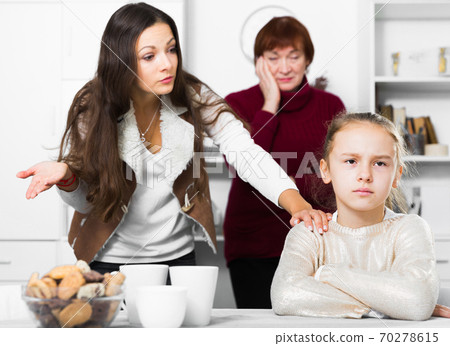 Offended little while mom and granny scolding her Offended little while mom and granny scolding her 70278615