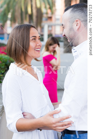 Young woman is flirting with boyfriend when her girlfriend is envying them Young woman is flirting with boyfriend when her girlfriend is envying them 70278713