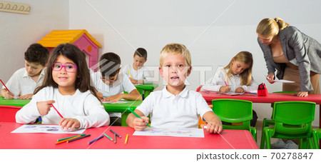 Cheerful school kids studying in classroom Cheerful school kids studying in classroom 70278847