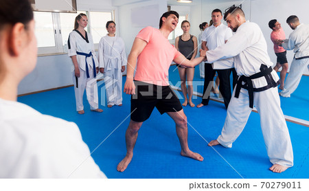 Coach explaining painful hold in taekwondo class Coach explaining painful hold in taekwondo class 70279011