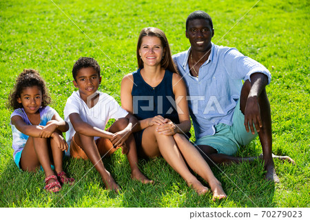 Family sitting on green lawn Family sitting on green lawn 70279023