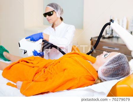 Woman removing hair from legs with laser 70279079
