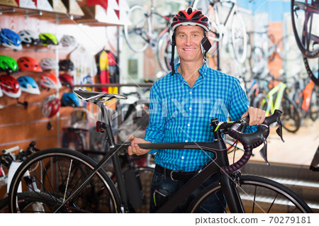 Smiling male customer picking new chosen bicycle 70279181