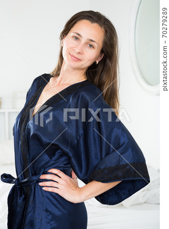 Cute woman in a blue silk robe in bedroom 70279289