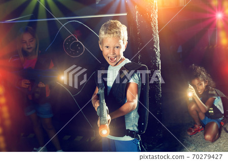 Excited little boy aiming laser gun at other players during lase Excited little boy aiming laser gun at other players during lase 70279427