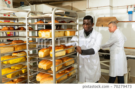 Baker pushing trolley with baked bread Baker pushing trolley with baked bread 70279473