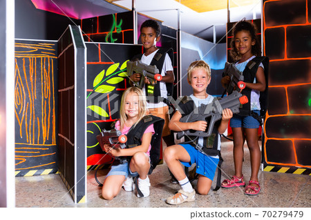 Joyful teens aiming laser guns at other players during lasertag game in dark room Joyful teens aiming laser guns at other players during lasertag game in dark room 70279479