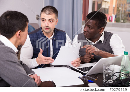 Three men are looking on documents and talking about it together Three men are looking on documents and talking about it together 70279519