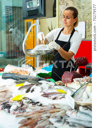 Saleswoman weighing shrimps on scales Saleswoman weighing shrimps on scales 70279577