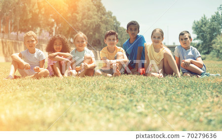 Group of happy kids friends resting on grass together in park Group of happy kids friends resting on grass together in park 70279636