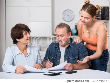 Adult couple is singing contract with their daughter Adult couple is singing contract with their daughter 70279863