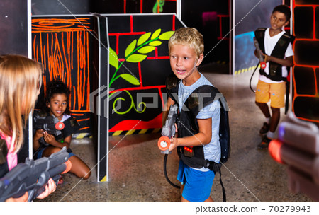 Positive teen boy standing with laser pistol in dark lasertag room during game with friends 70279943