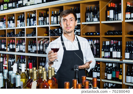 Seller man wearing apron suggesting to try glass of wine 70280040