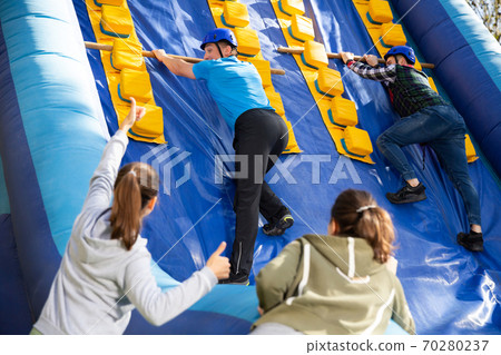 Friends climbing on inflatable slide in amusement park 70280237