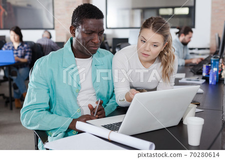 Girl helping African male colleague 70280614