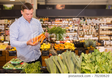 Male consumer choosing carrots in supermarket Male consumer choosing carrots in supermarket 70280620