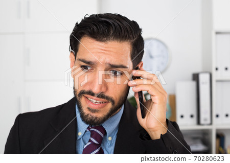 Adult man is surprised while talking phone with his partner 70280623