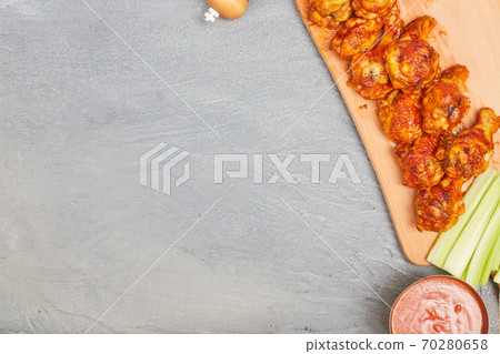 Buffalo chicken wings on a wooden board with celery on a concrete background, top view, copy space Buffalo chicken wings on a wooden board with celery on a concrete background, top view, copy space 70280658