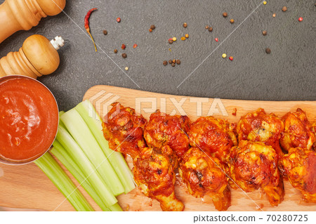 Buffalo chicken wings on a wooden board with celery, top view, copy space Buffalo chicken wings on a wooden board with celery, top view, copy space 70280725