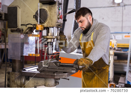 Man mechanic using drilling machine in workshop Man mechanic using drilling machine in workshop 70280730