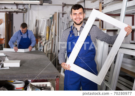 Young laborer is demonstrating the window frame Young laborer is demonstrating the window frame 70280977