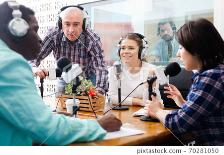Multinational group of cheerful young adults emotionally discussing in radio studio 70281050