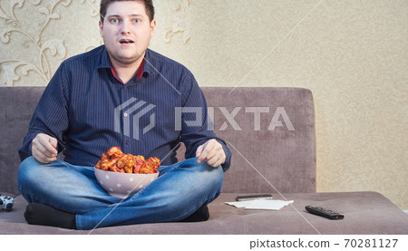 man on the couch with a plate of Buffalo Chicken Wings, copy space man on the couch with a plate of Buffalo Chicken Wings, copy space 70281127