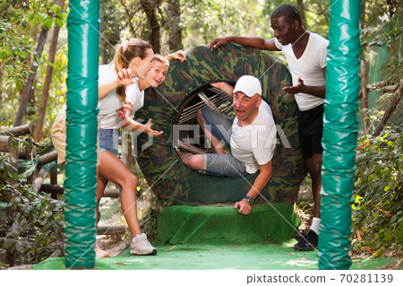 Friends passing obstacles at adventure park 70281139