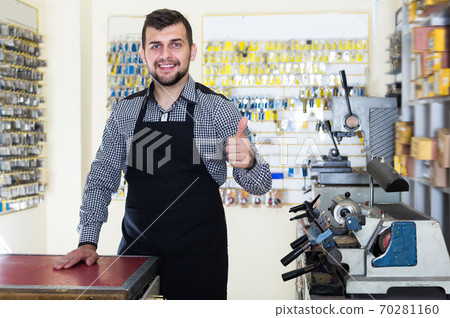 Adult worker demonstrating tools for making keys 70281160