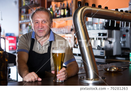 Adult barman is giving beer with foam to client Adult barman is giving beer with foam to client 70281263