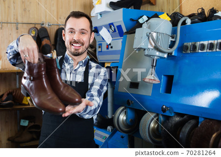 Male worker demonstrating repaired shoes in shoe Male worker demonstrating repaired shoes in shoe 70281264