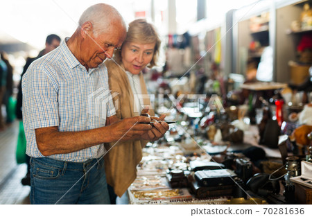 Mature couple choose smoking pipe on flea market Mature couple choose smoking pipe on flea market 70281636
