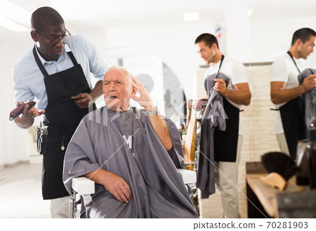 Dissatisfied elderly client with perplexed African hairdresser Dissatisfied elderly client with perplexed African hairdresser 70281903