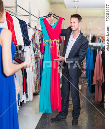 man smiling and offering dresses in women clothing store man smiling and offering dresses in women clothing store 70281977
