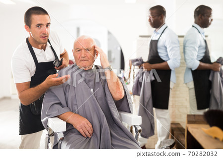 Shocked elderly man with confused hairdresser 70282032