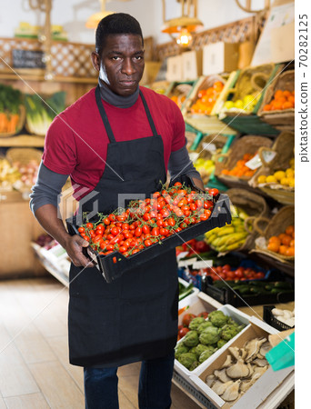 Confident salesman carrying box with tomatoes Confident salesman carrying box with tomatoes 70282125