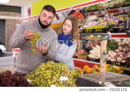 Young couple picks grapes at the grocery store Young couple picks grapes at the grocery store 70282158