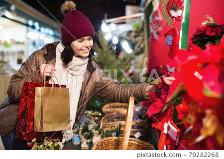 Girl buying floral compositions at Christmas market Girl buying floral compositions at Christmas market 70282268