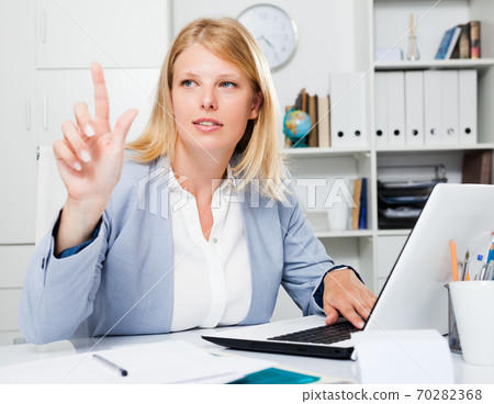 Business lady pointing to invisible screen Business lady pointing to invisible screen 70282368