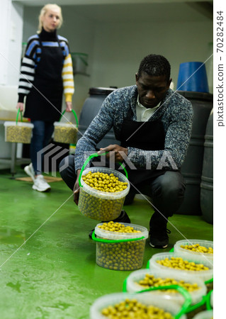Man filling plastic bucket with pickled olives Man filling plastic bucket with pickled olives 70282484