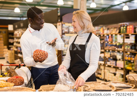 Saleswoman helping man to choose bulk products Saleswoman helping man to choose bulk products 70282485