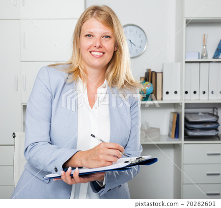 Woman in business suit holding folder Woman in business suit holding folder 70282601