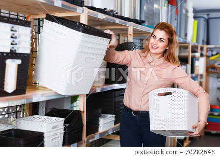 Woman choosing different plastic basket for storage in household shop Woman choosing different plastic basket for storage in household shop 70282648