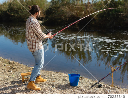 Happy fisherman pulls fish out of the river Happy fisherman pulls fish out of the river 70282840