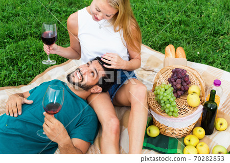 Adult man is lying on the lap of girlfriend in time picnic in the park. 70282853